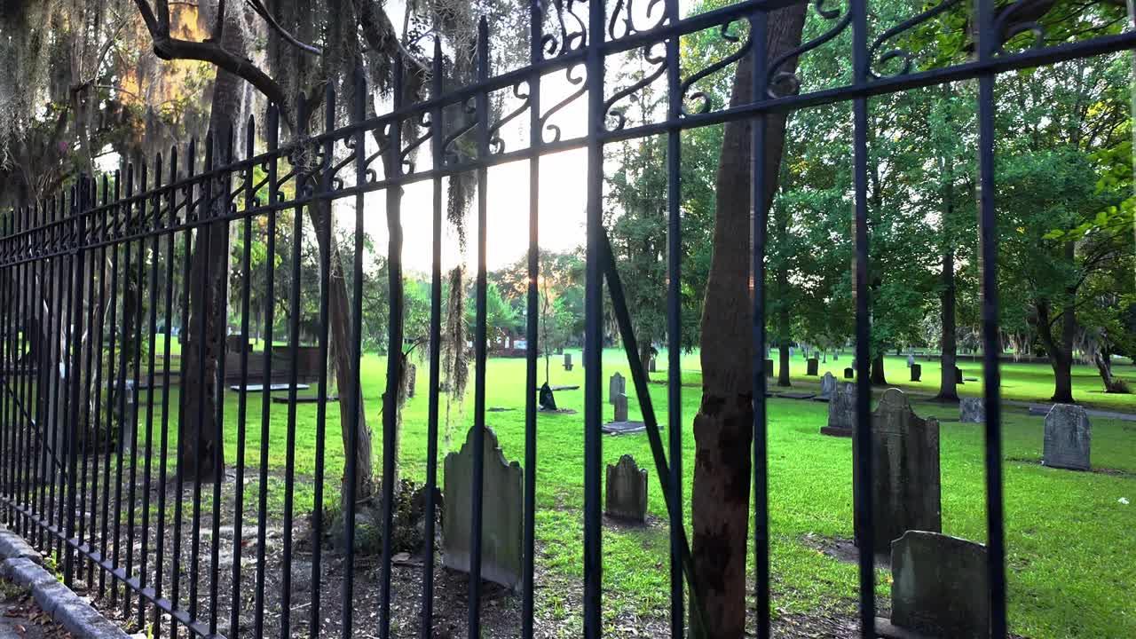 Sunset through the fence of a historic and creepy cemetery in Savannah, Georgia
