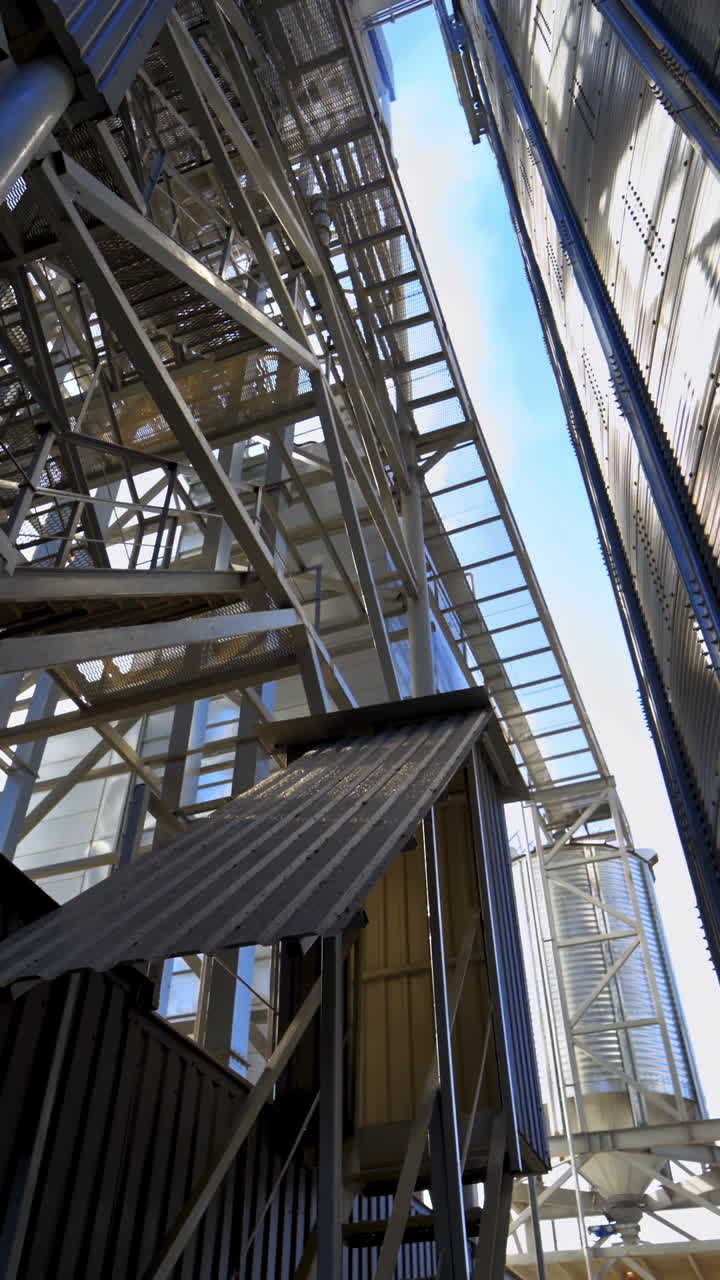 Industrial equipment outdoors. Large metal terminals. Silver grain elevators on a modern plant for storing agricultural products. Close-up. Vertical video
