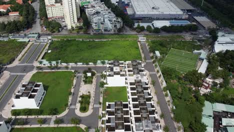 Drone-tilted-down-dolly-above-condos-and-green-lawn-space-by-apartment-buildings-in-vietnam