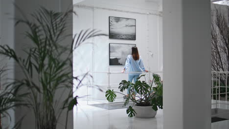 thoughtful woman looking paintings on wall. focused visitor watching artwork