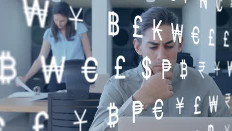 Animation-of-currency-symbols-against-thoughtful-biracial-man-using-laptop-at-office