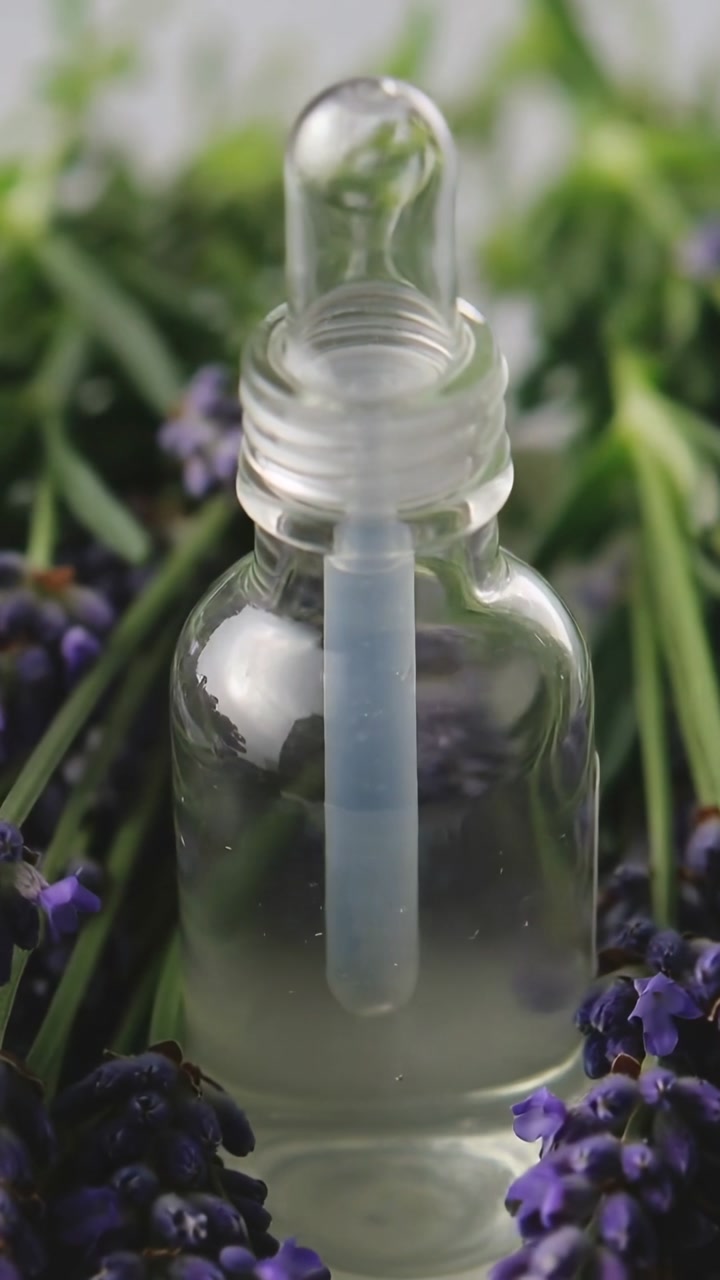 Vertical video: Camera moving revealing dropper bottle on gray table to show pipette and lavender