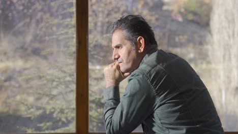 un hombre maduro y solitario en casa mirando por la ventana. conceptos de salud mental y depresión.