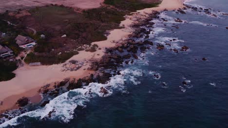 blue waves from the pacific ocean crash in front of beautiful luxury rental villas in oaxaca mexico