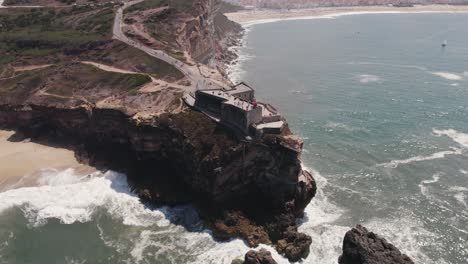 Luftumkreisung-über-Berühmtem-Leuchtturm-Auf-Felsiger-Klippe,-Nazaré---Atlantikküste