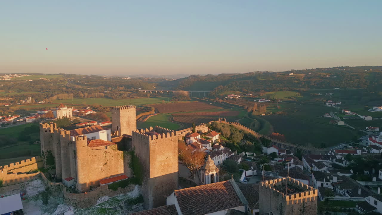 Aerial view fortress towers surrounded by  village at sunset light.