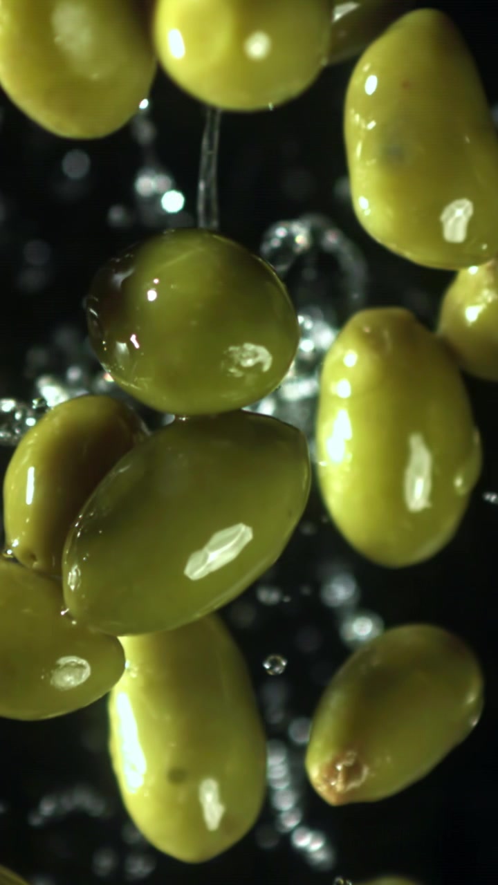 Olive verdi fresche che cadono nell'acqua con schizzi