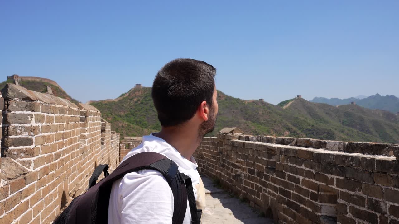 hombre de pie en la gran muralla de china, señalando con un sentido de reflexión en un día soleado