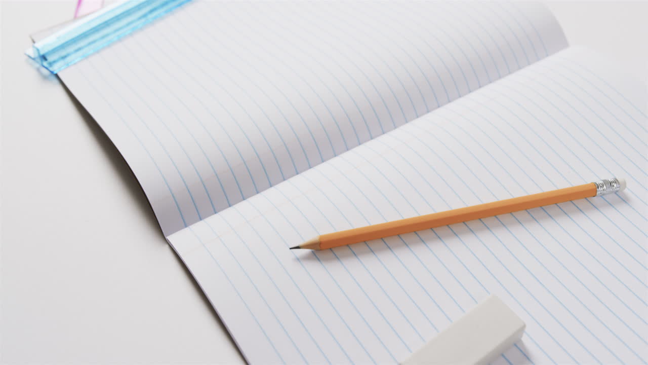 Close up of open notebook with school stationery on grey background, in slow motion