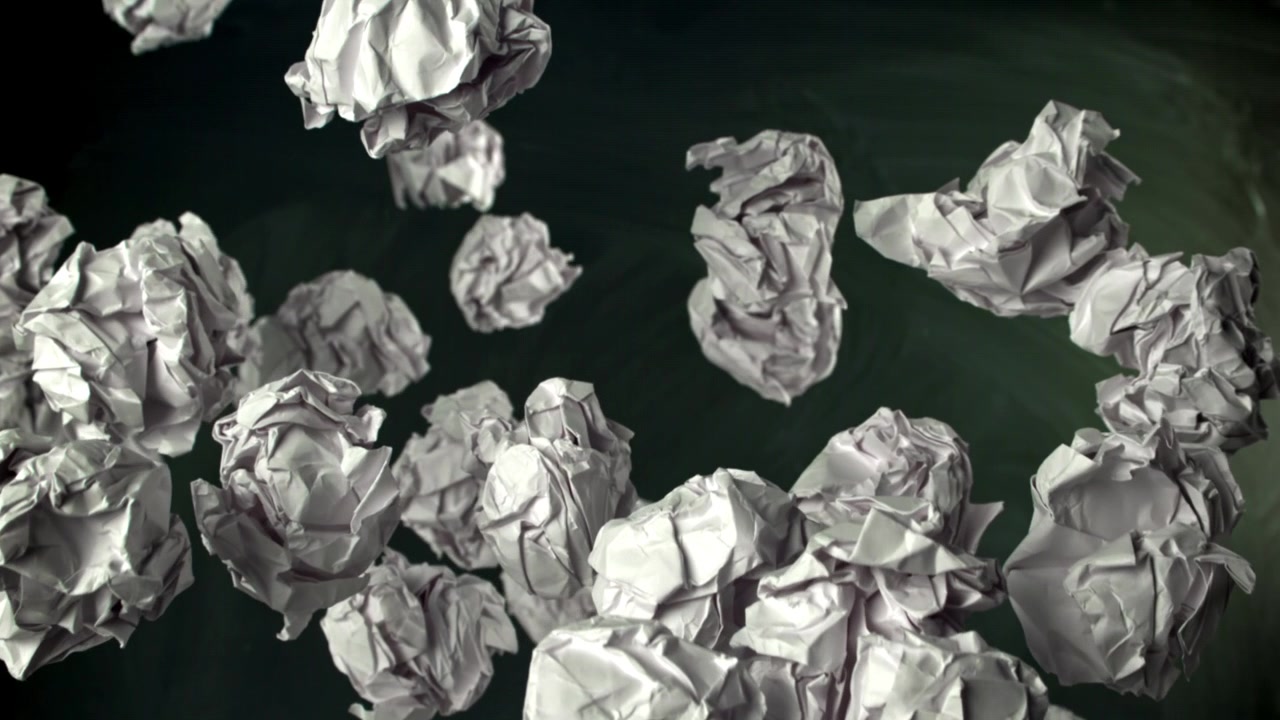 Palline di carta accartocciate che fluttuano verso l'alto contro una lavagna scura