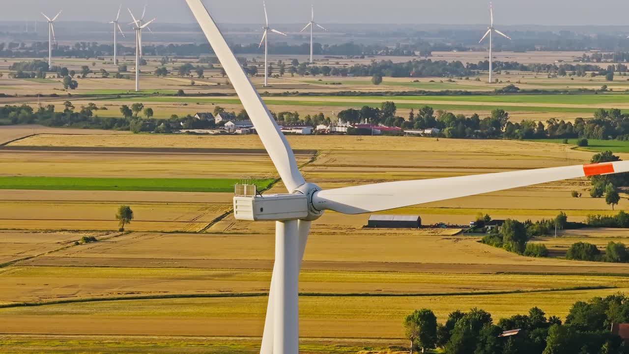 Slow motion drone view, wind turbine rotate in Poland farmland, golden sunset
