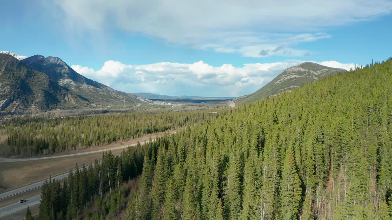 vista aérea de drones volando hacia adelante para revelar la carretera detrás del bosque que atraviesa la región montañosa