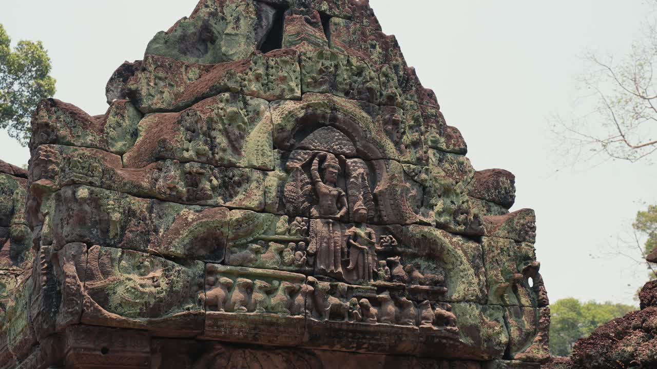 Vista dell'antico frontone in pietra con rilievo intagliato di una divinità e superficie consumata ad Angkor Wat in Cambogia, che mostra l'architettura storica, l'arte sacra e il patrimonio culturale