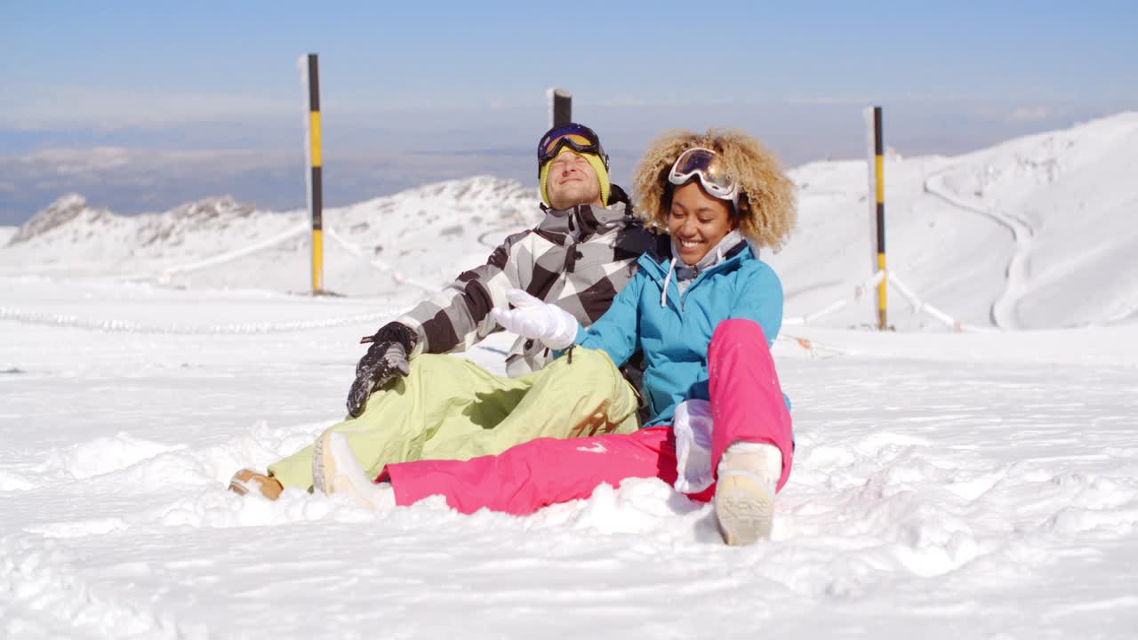 pareja sentada en la nieve en la pendiente de esquí