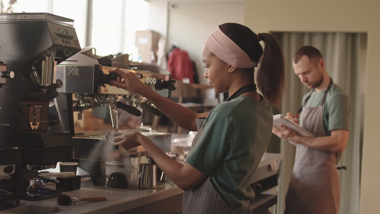 Barista donna che pulisce la macchina del caffè al bar