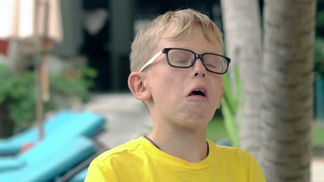 un niño pequeño con camiseta amarilla y gafas muestra el cubo de rubik