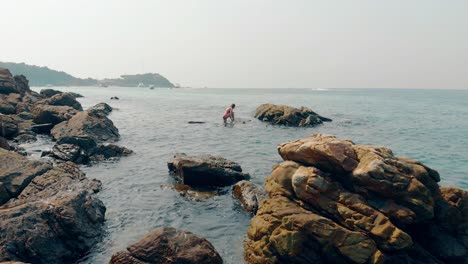 girl stands on stone and straightens dark brown hair