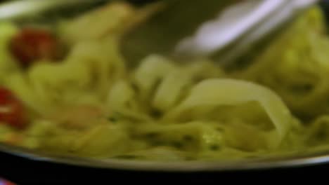 chef revuelve pasta de mariscos con salsa blanca con camarones y tomates con lengua