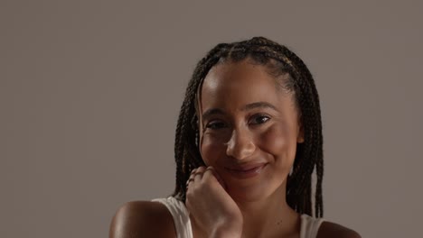 studio beauty shot of smiling young woman with long braided hair against neutral background