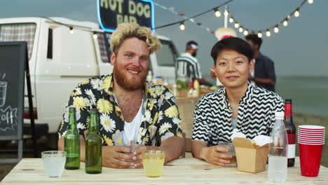 portrait of joyous caucasian man and asian woman on summer festival