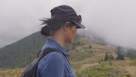 tracking portrait shot of woman hiking along mountain trail in beautiful landscape on cloudy overcast day in tennessee