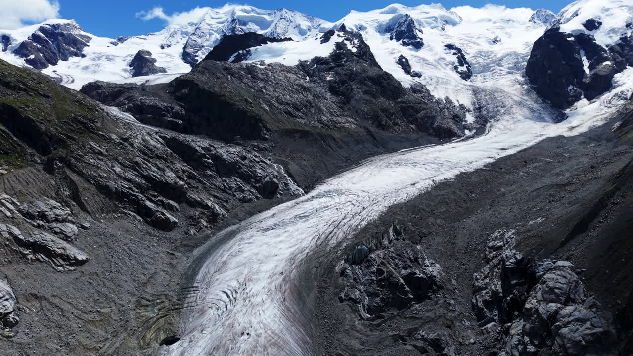 Drone tilts up and retreats above icy glacial stream and rocky slopes