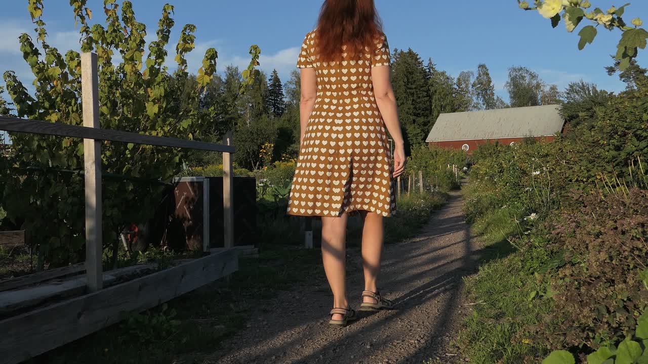 Woman in garden walking to country house in countryside