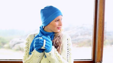 Cute-blonde-drinking-from-mug-in-a-ski-lodge