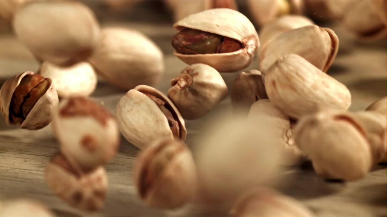 Close-up Slow Motion of Pistachios Falling on Wooden Surface