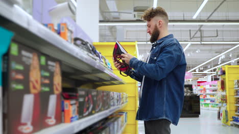 man looking at an iron in a supermarket