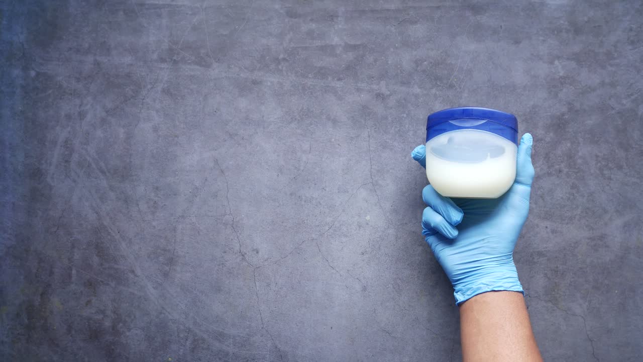 vista superior de la mano del hombre usando jalea de petróleo sobre fondo negro ,