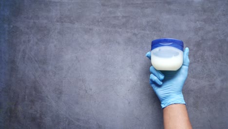 Top-view-of-man-hand-using-petroleum-jelly-on-black-background-,