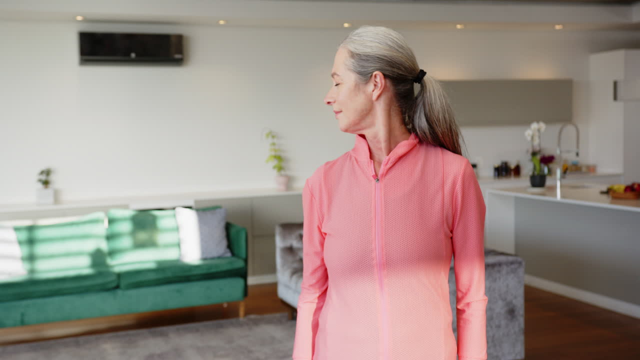 Smiling woman in pink jacket standing in modern living room at home, copy space
