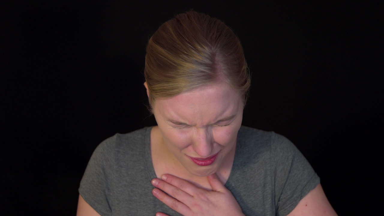 A coughing woman. A young woman is choking while coughing. He can't get air. These could be COVID-19 symptoms. Slowmotion video