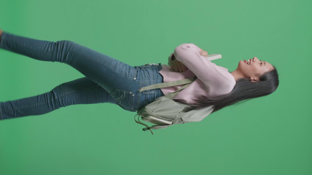 책 을 들고 녹색 스크린 스튜디오 에서 고 있는 아시아 여성 학생 의 측면 시각