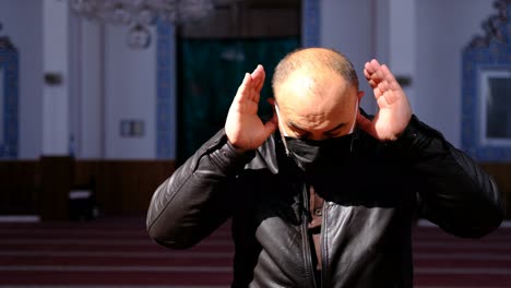 el hombre usa una máscara debido al coronavirus reza en la mezquita