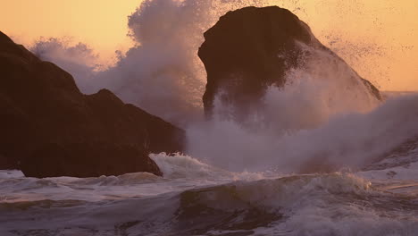 sea stacks hit by foamy waves on sunset beach