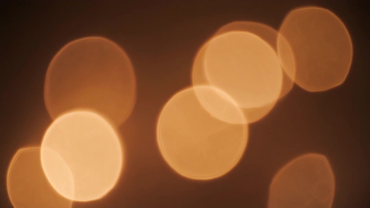 Abstraktit kultaiset bokeh-valot hohtavat pimeällä taustalla