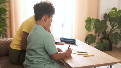 young boy engaged in drawing activity at home with an adult