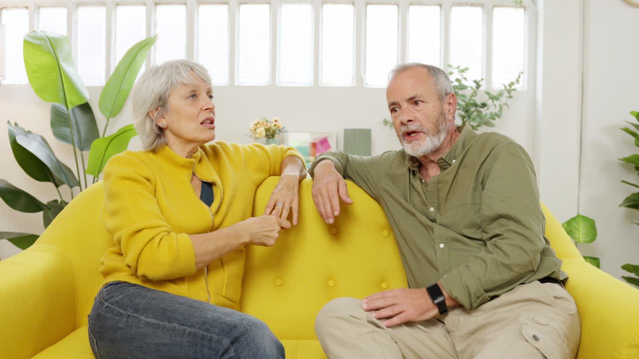 Pareja mayor hablando en un sofá