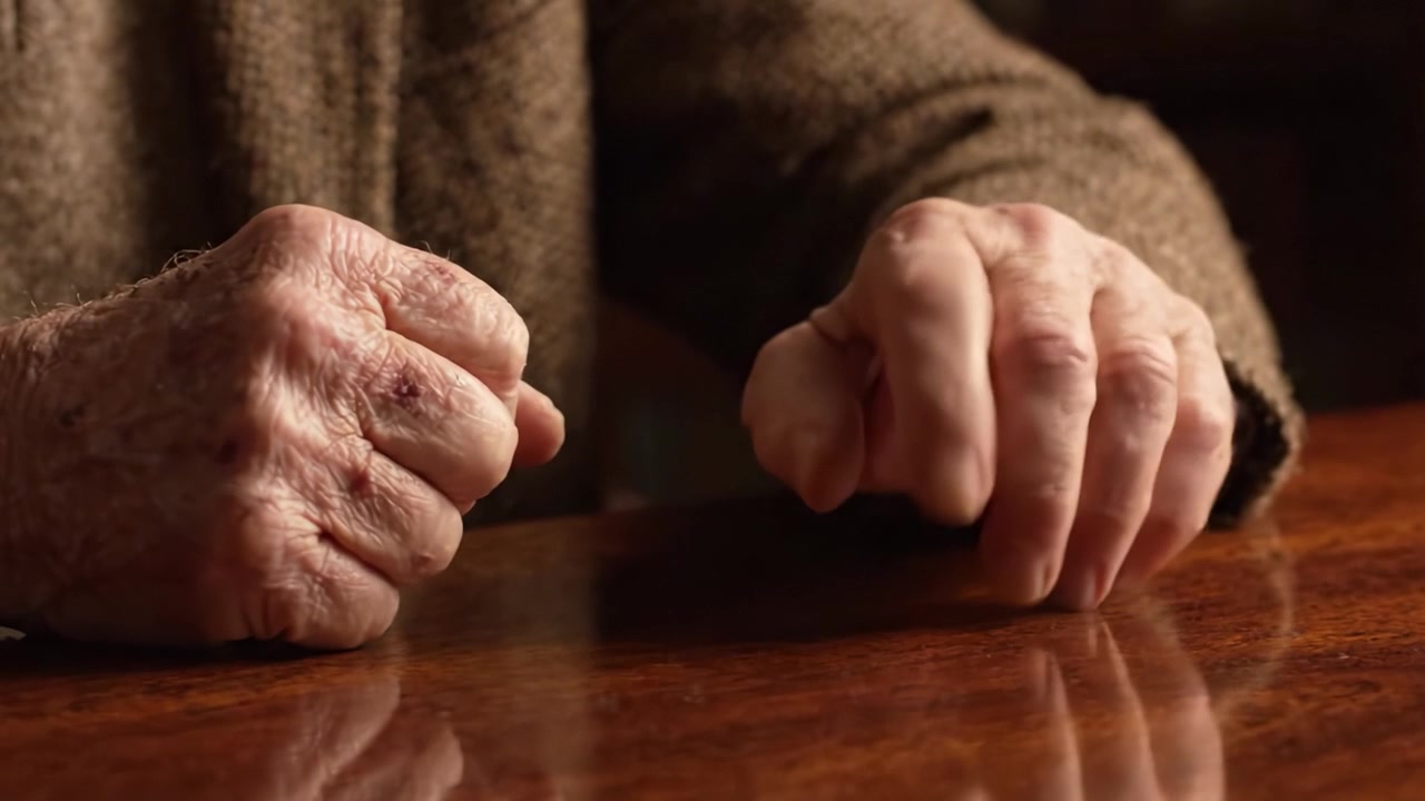 Una riflessione intima sul passare del tempo: Catturando il gesto sottile di mani segnate dal tempo appoggiate su una superficie di legno.