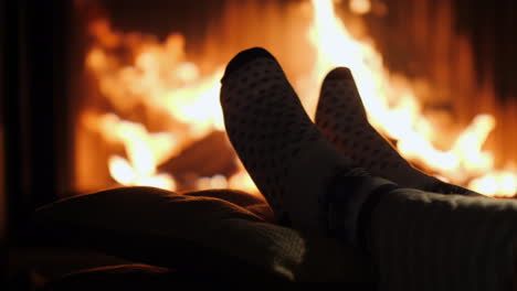 legs in socks are heated by the fireplace in winter evening