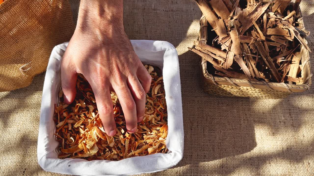 Person's hand checking dried orange peels in a basket