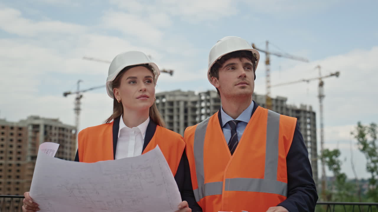 Two engineers study blueprint at city construction site closeup. Professionals