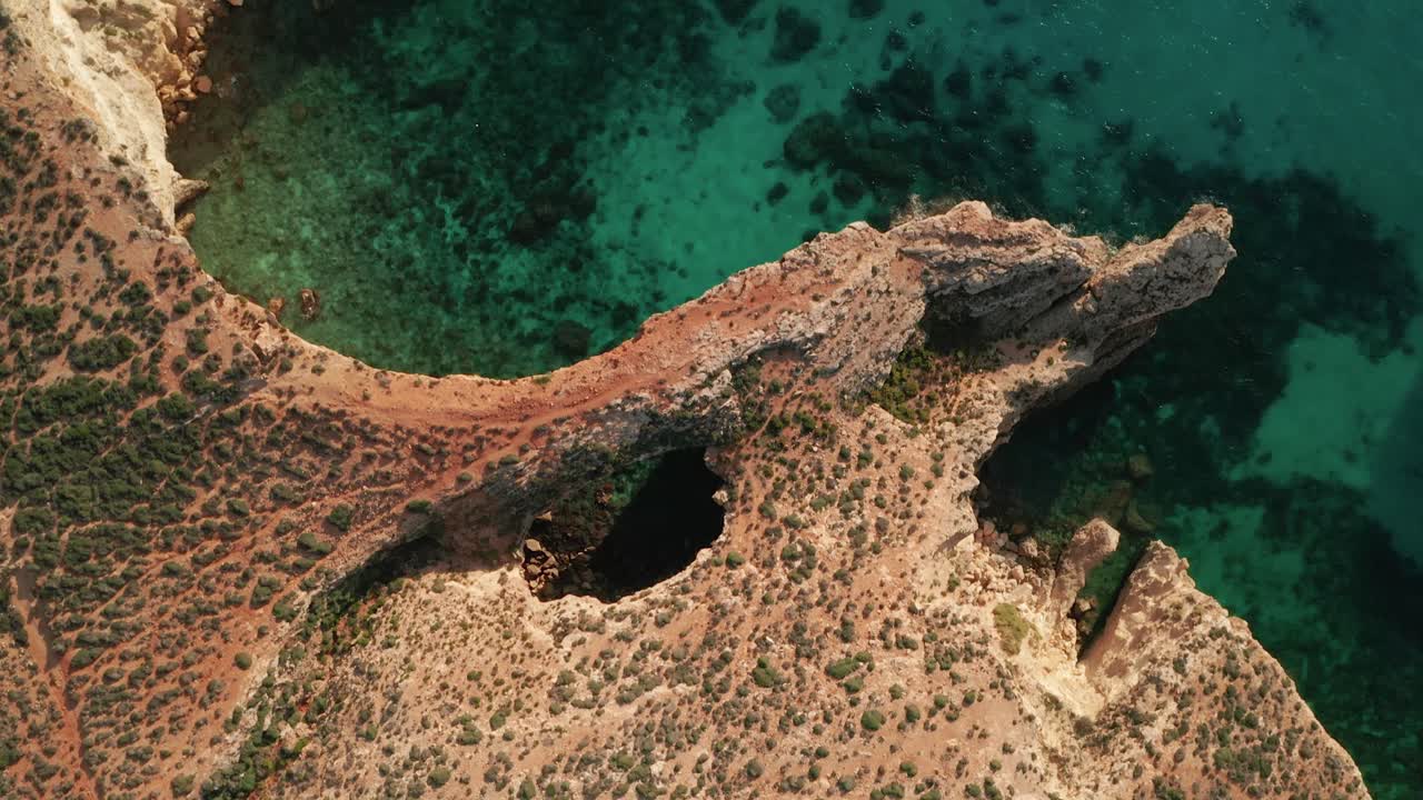 Aerial overhead drone footage of the rugged coastal rock formations and caves near the popular Blue Lagoon in Comino island, Malta