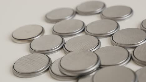 lot of metallic button batteries on white 4k panning footage