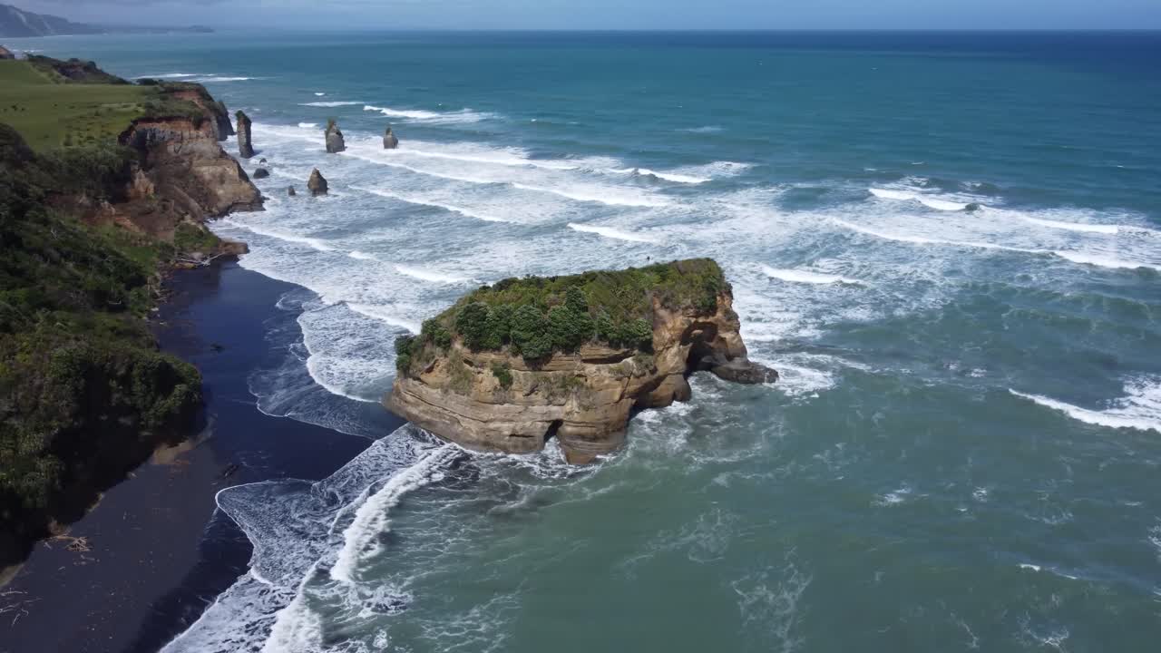 Drone view of the coast, rocks and ocean on a sunny summer day at Three Sisters and Elephant Rock, New Zealand.