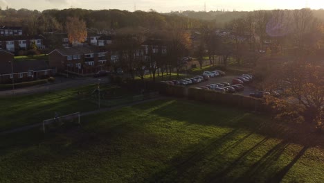 long sunset autumn shadows across british neighbourhood school soccer field aerial view
