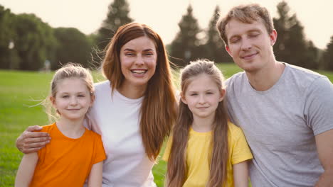 porträt einer glücklichen familie, die lächelt und in die kamera schaut, während sie zeit miteinander im park verbringt