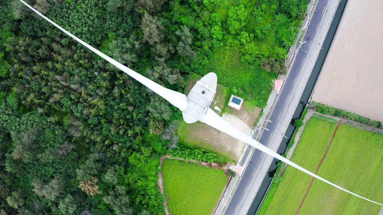 움직이는 풍력 터빈, 숲 나무 및 지상의 농경지의 공중을 닫습니다.